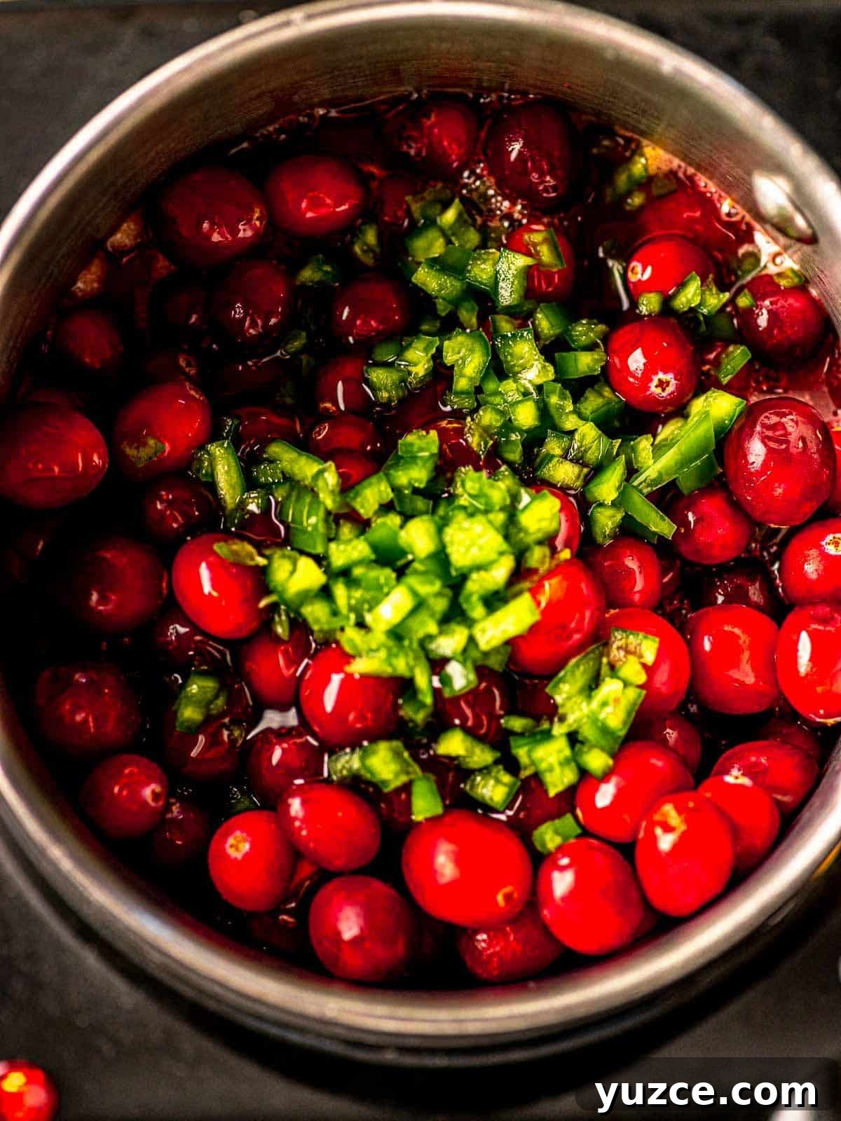Cranberry Jalapeño Cream Cheese Dip Recipe for Holiday Parties 4 Cranberries and diced jalapeños in a saucepan.