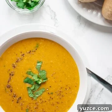a bowl of moroccan lentil soup on a table alongside a plate of rolls