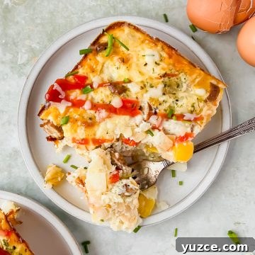 Ultimate Cheesy Loaded Hashbrown Casserole Recipe 12 slice of loaded hashbrown casserole on white serving plate beside egg shells.