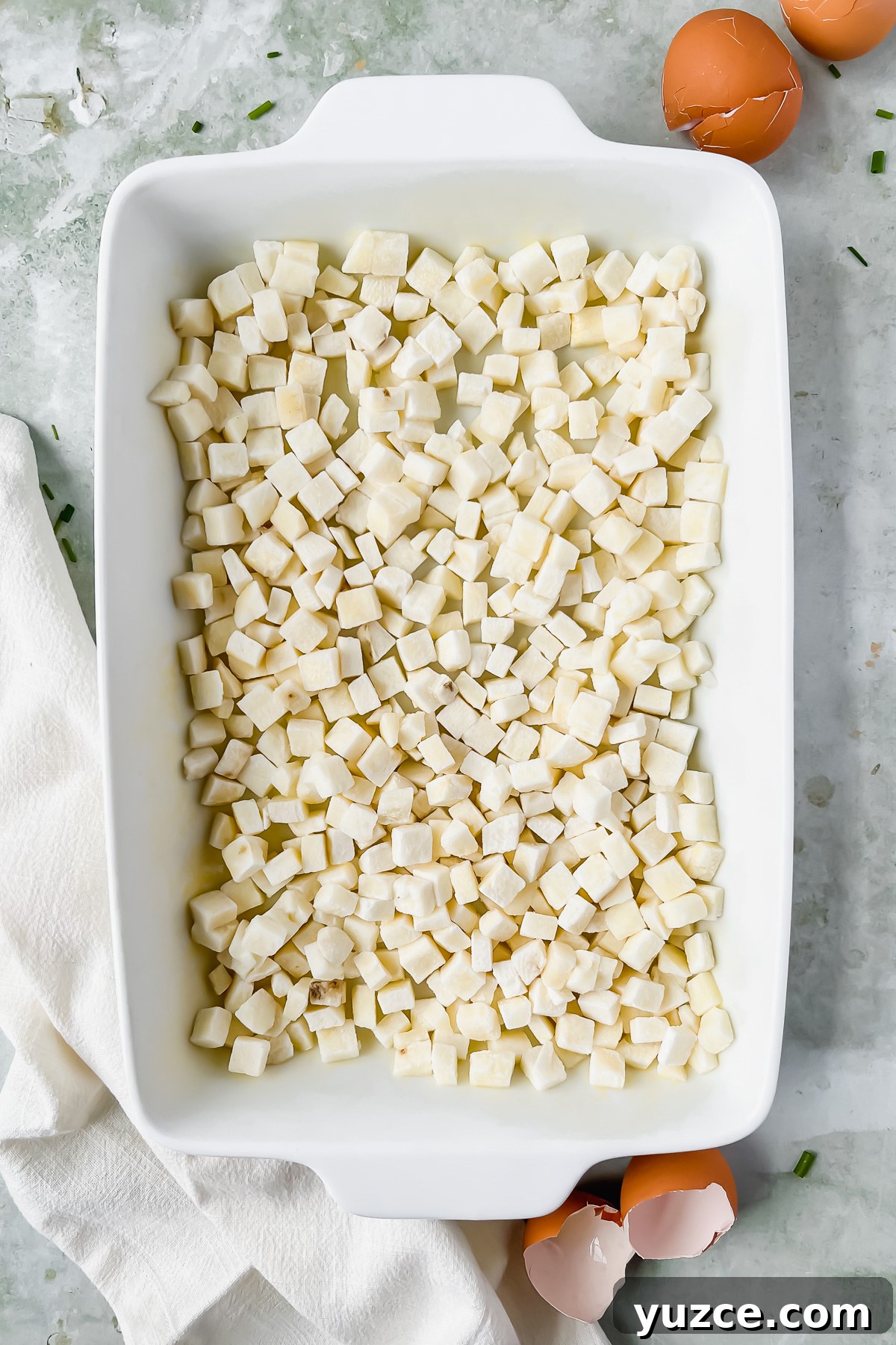 Ultimate Cheesy Loaded Hashbrown Casserole Recipe 6 diced potatoes in white rectangular baking dish.