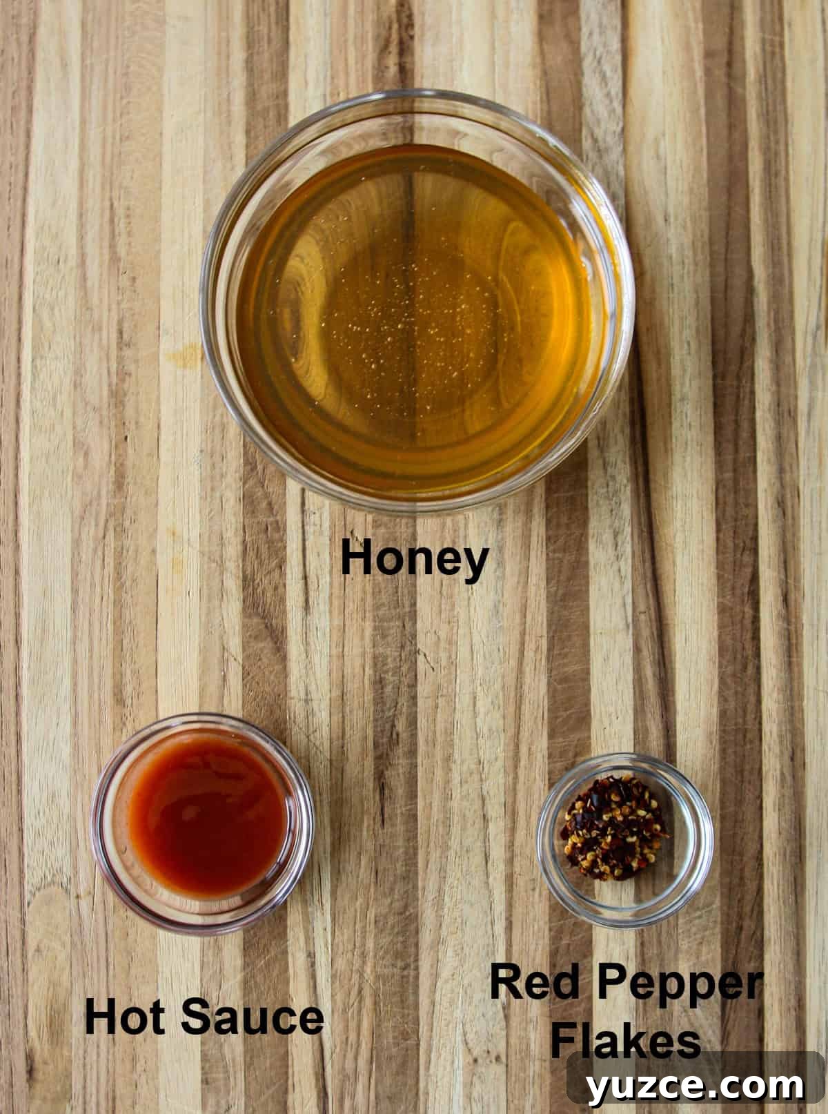 Homemade Hot Honey Recipe for Spicy-Sweet Drizzling and Cooking 3 The recipe ingredients in glass bowls on a wooden board.