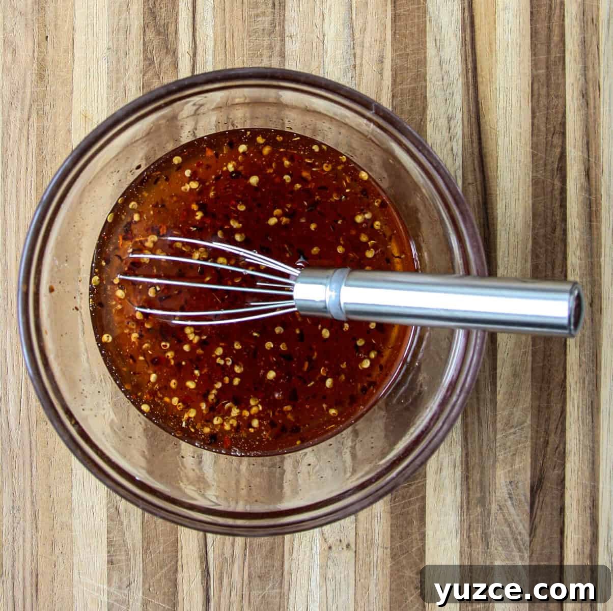 Homemade Hot Honey Recipe for Spicy-Sweet Drizzling and Cooking 4 The ingredients for the hot honey recipe in a glass bowl with a wire whisk.