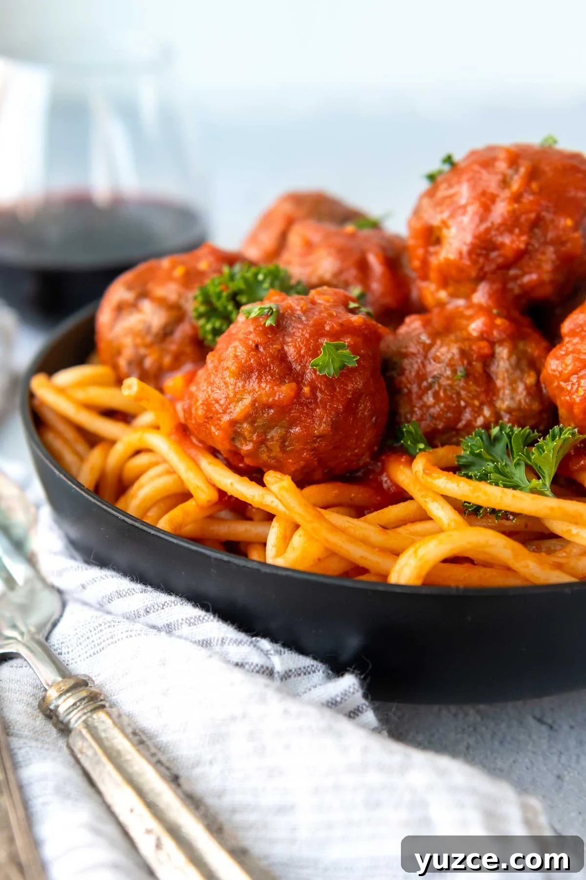 Gluten-Free All-Beef Meatballs Without Breadcrumbs 2 meatballs served over pasta in a black bowl.