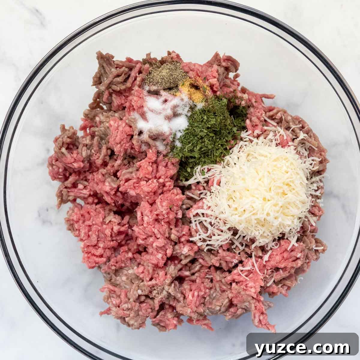 Gluten-Free All-Beef Meatballs Without Breadcrumbs 3 ingredients for meatballs in a large glass bowl.