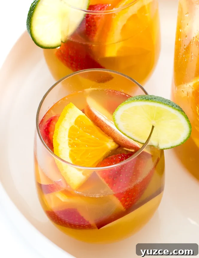Refreshing White Wine Sangria Recipe with Fresh Fruit 2 glasses filled with sangria rimmed with lime slices