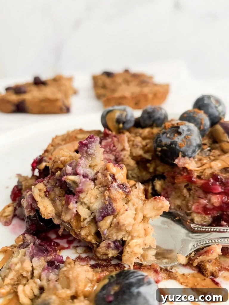 Peanut Butter Banana Berry Baked Oats — Protein-Packed Breakfast 2 close up of a slice of baked oatmeal with a fork taking a bite of it