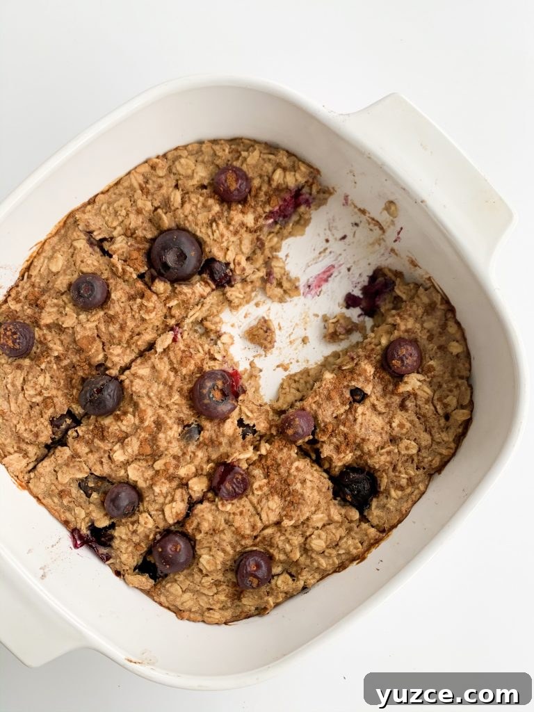 Peanut Butter Banana Berry Baked Oats — Protein-Packed Breakfast 3 overhead shot of peanut butter banana berry baked oatmeal in a white baking dish with one slice missing