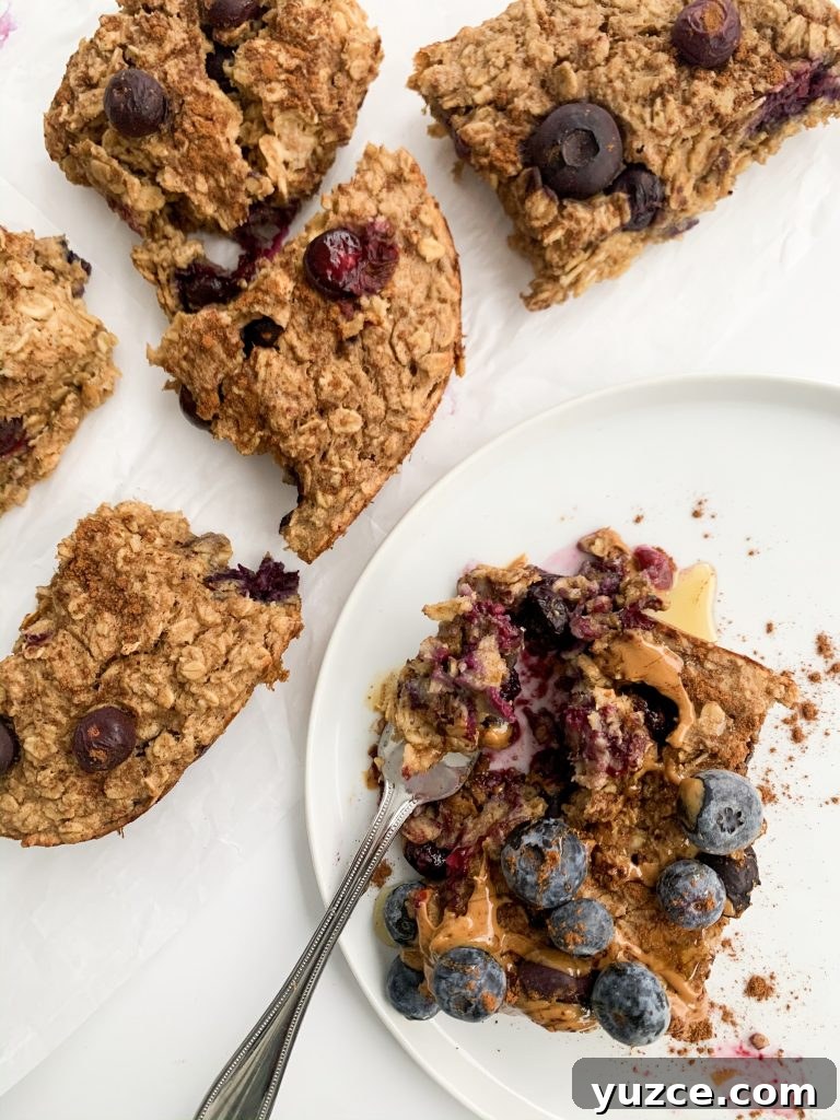 Peanut Butter Banana Berry Baked Oats — Protein-Packed Breakfast 6 white background with a plate with a slice of oatmeal on it and a sheet of parchment paper with more slices