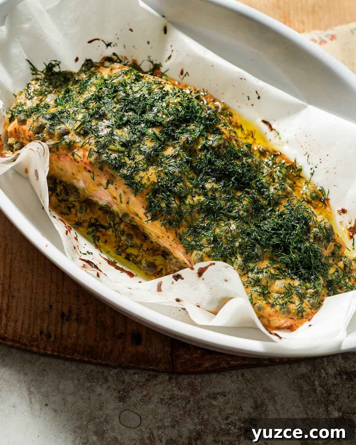 Dijon-Baked Salmon with Fresh Dill and Lemon 2 Dijon mustard dill salmon after being cooked in a baking dish with parchment paper.