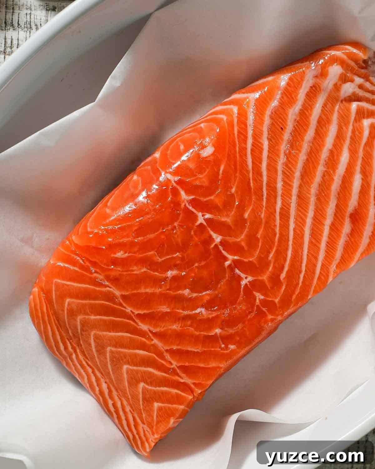 Dijon-Baked Salmon with Fresh Dill and Lemon 4 A salmon fillet in a baking dish lined with parchment paper.