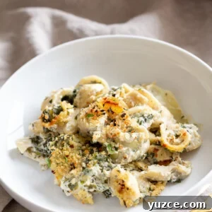 Creamy Vegan Spinach and Artichoke Pasta Bake Recipe 3 a serving of vegan spinach and artichoke pasta bake on a white plate