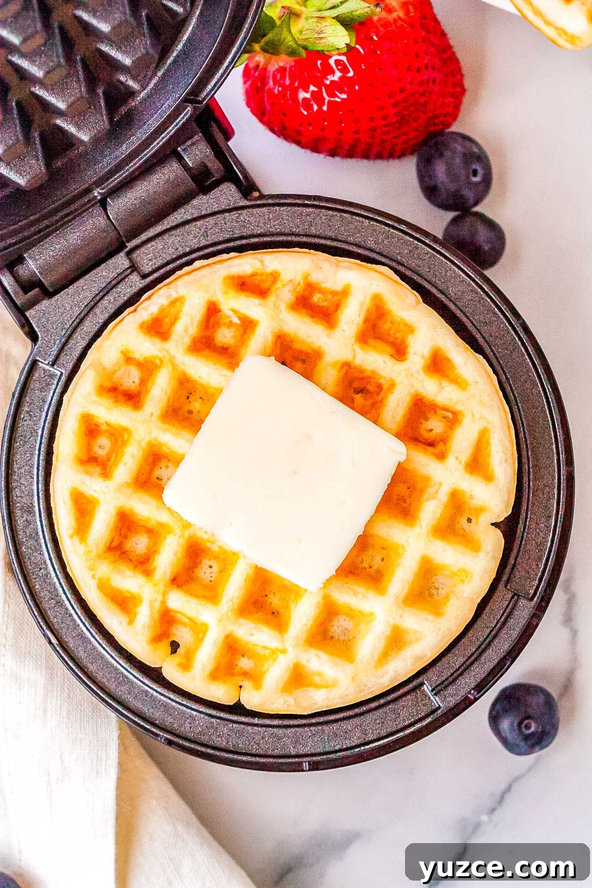 Crispy Dash Waffle Maker Recipes for Quick Breakfasts 2 The finished Dash waffle make recipe in the waffle maker with a pad of butter on top of the waffle.