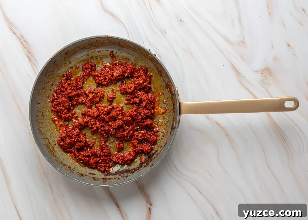 Chipotle Chorizo Bean Dip Recipe — Smoky Spicy Party Dip 4 Overhead view of fresh pork chorizo cooking in a skillet, browned and crumbled with rendered orange-red oil in the pan.
