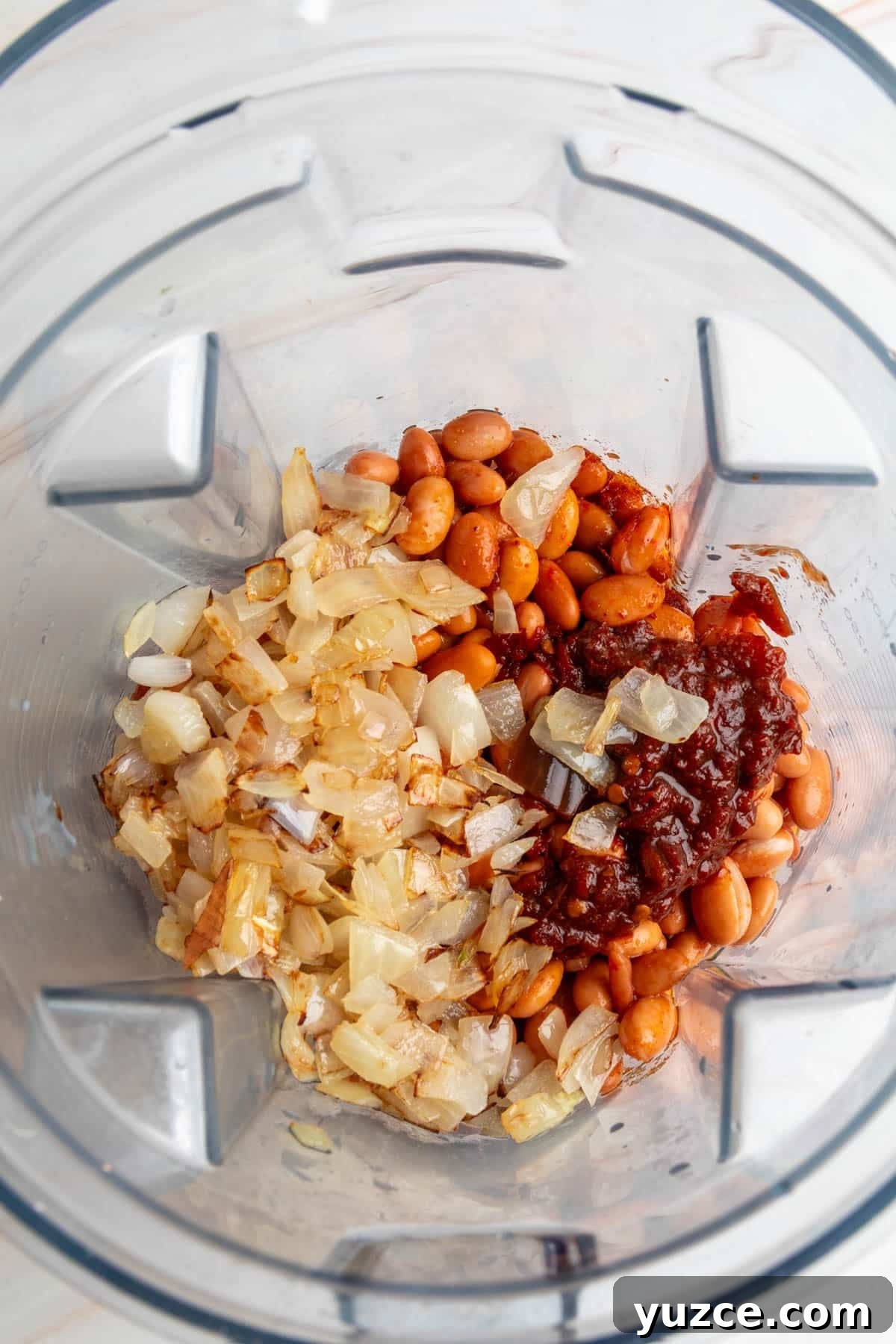 Chipotle Chorizo Bean Dip Recipe — Smoky Spicy Party Dip 5 Blender filled with pinto beans, sautéed onions, and chipotle in adobo sauce before blending.