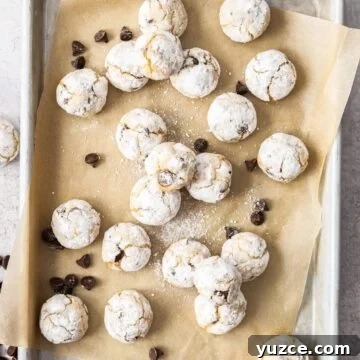 Almond Flour Chocolate Chip Cookies on a baking paper lined tray, with some chocolate chips sprinkled around.