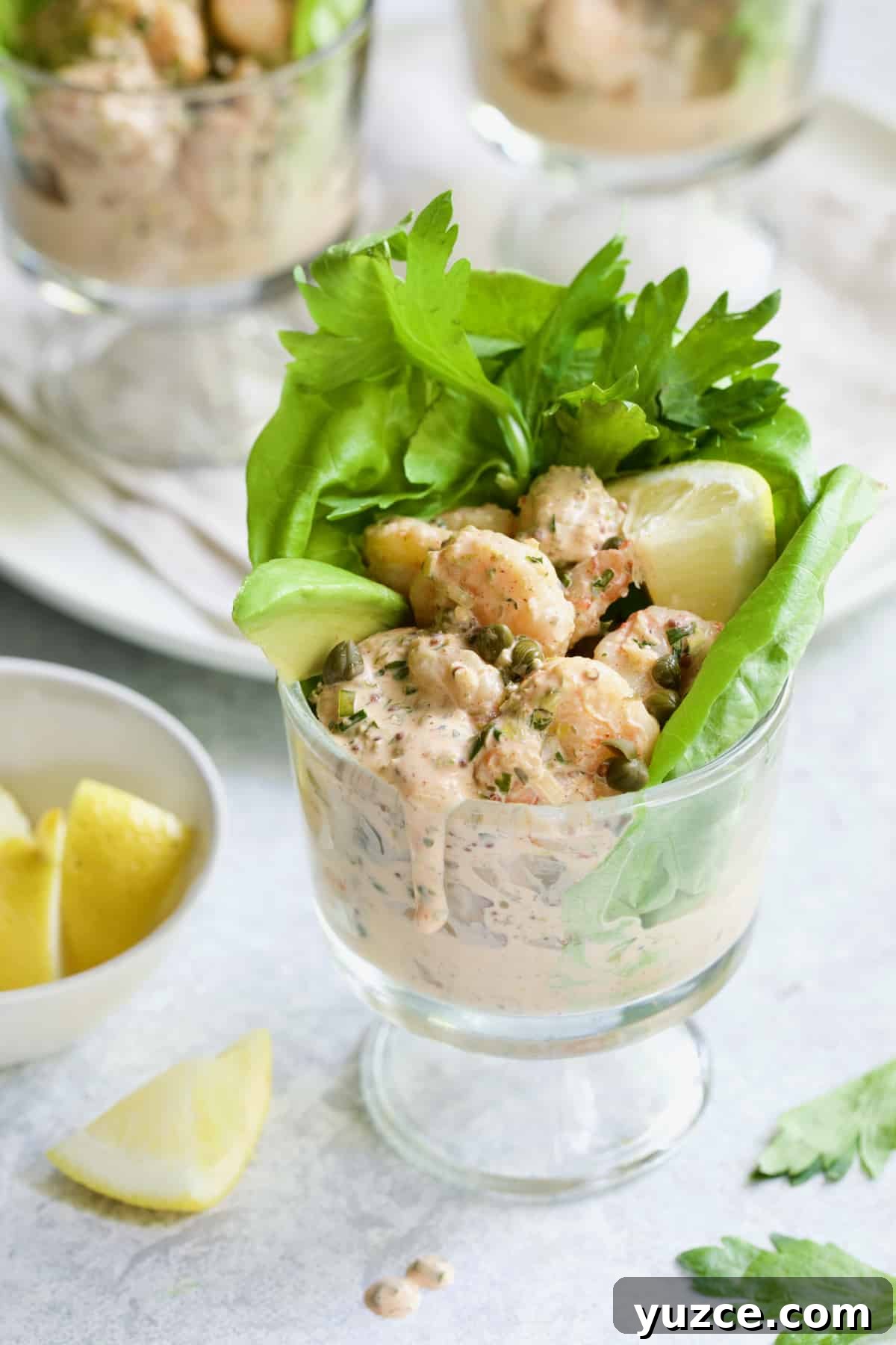 Shrimp Cocktail with Sriracha Remoulade Sauce 2 Sriracha Shrimp Remoulade Cocktail in footed glass with sauce dripping down the side.
