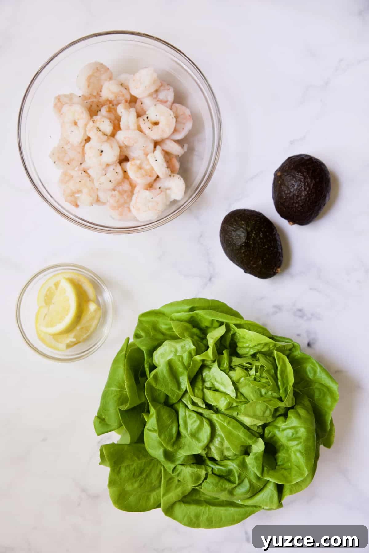 Shrimp Cocktail with Sriracha Remoulade Sauce 4 Photo of cooked shrimp, lemon wedges, avocados and lettuce.