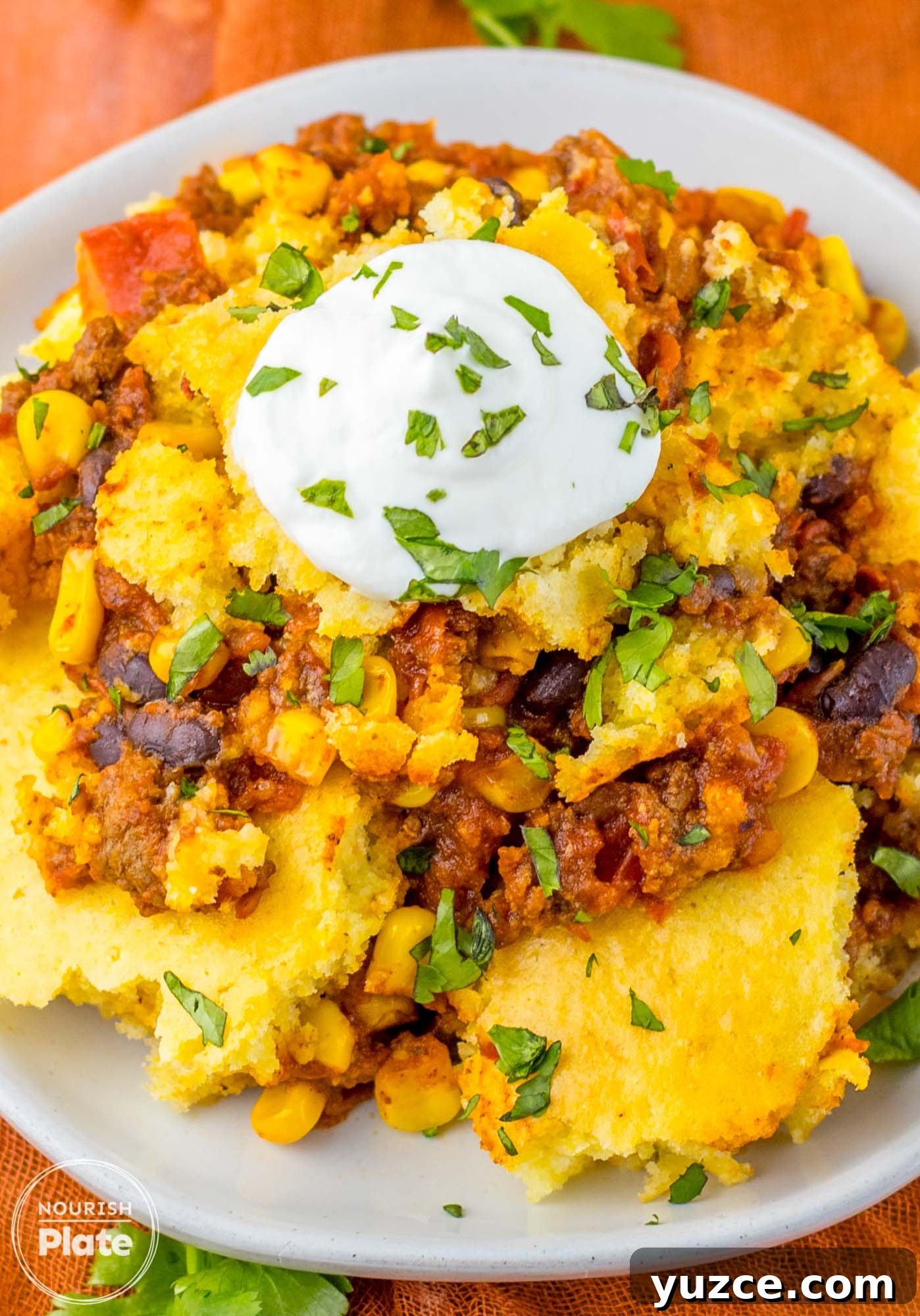 Creamy Cornbread Casserole with Cheesy Corn Topping 2 Plated portion of cornbread casserole topped with a dollop of sour cream