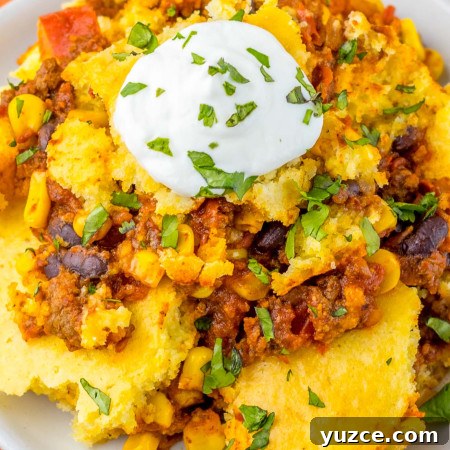 Creamy Cornbread Casserole with Cheesy Corn Topping 11 Plated portion of cornbread casserole topped with a dollop of sour cream