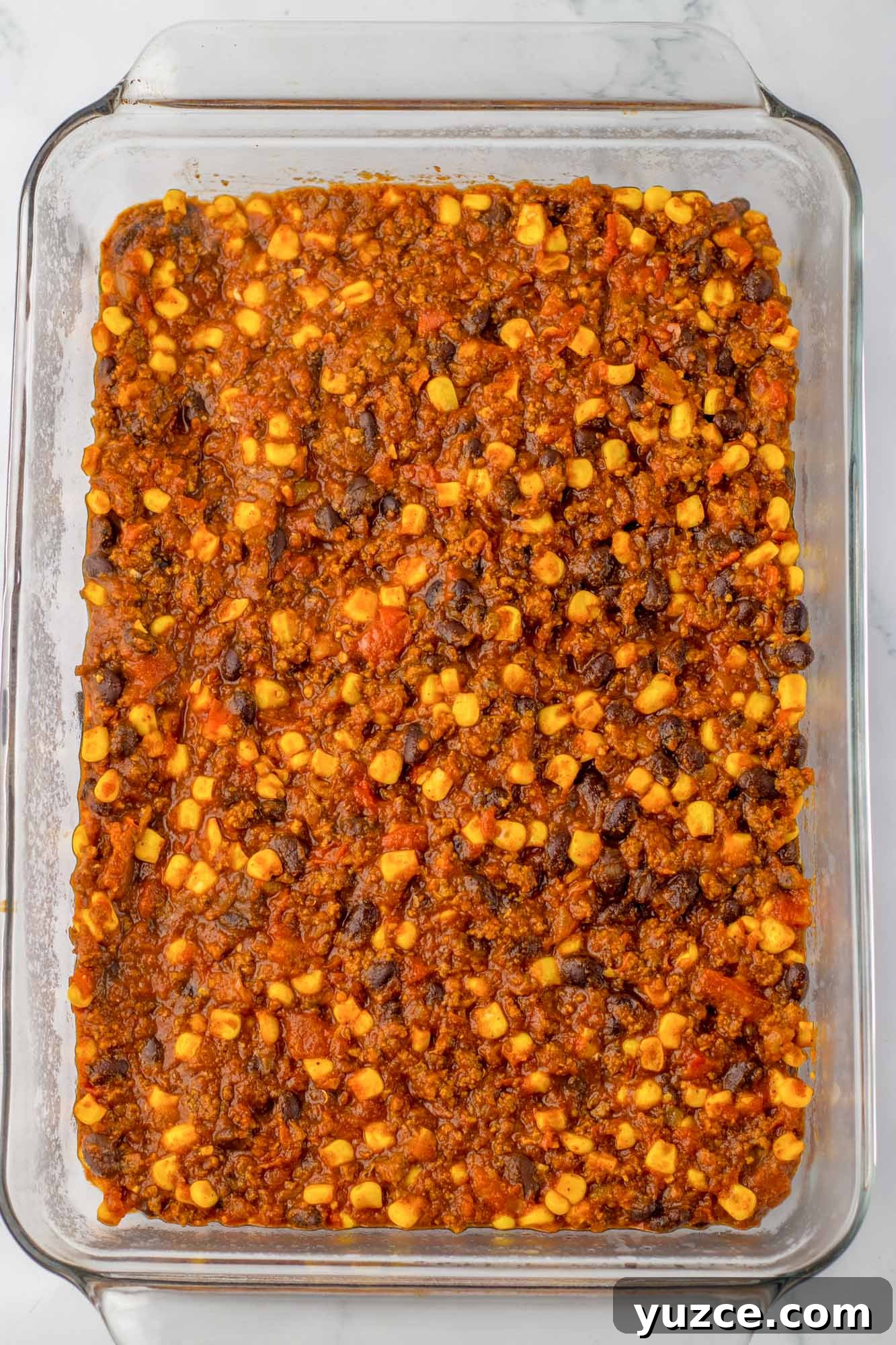 Creamy Cornbread Casserole with Cheesy Corn Topping 7 Chili mixture in a 9x13 inch pan, spreaded