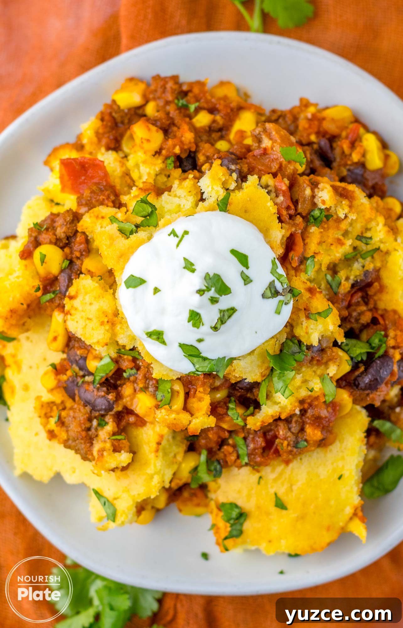 Creamy Cornbread Casserole with Cheesy Corn Topping 10 Overhead shot of plated cornbread casserole topped with sour cream