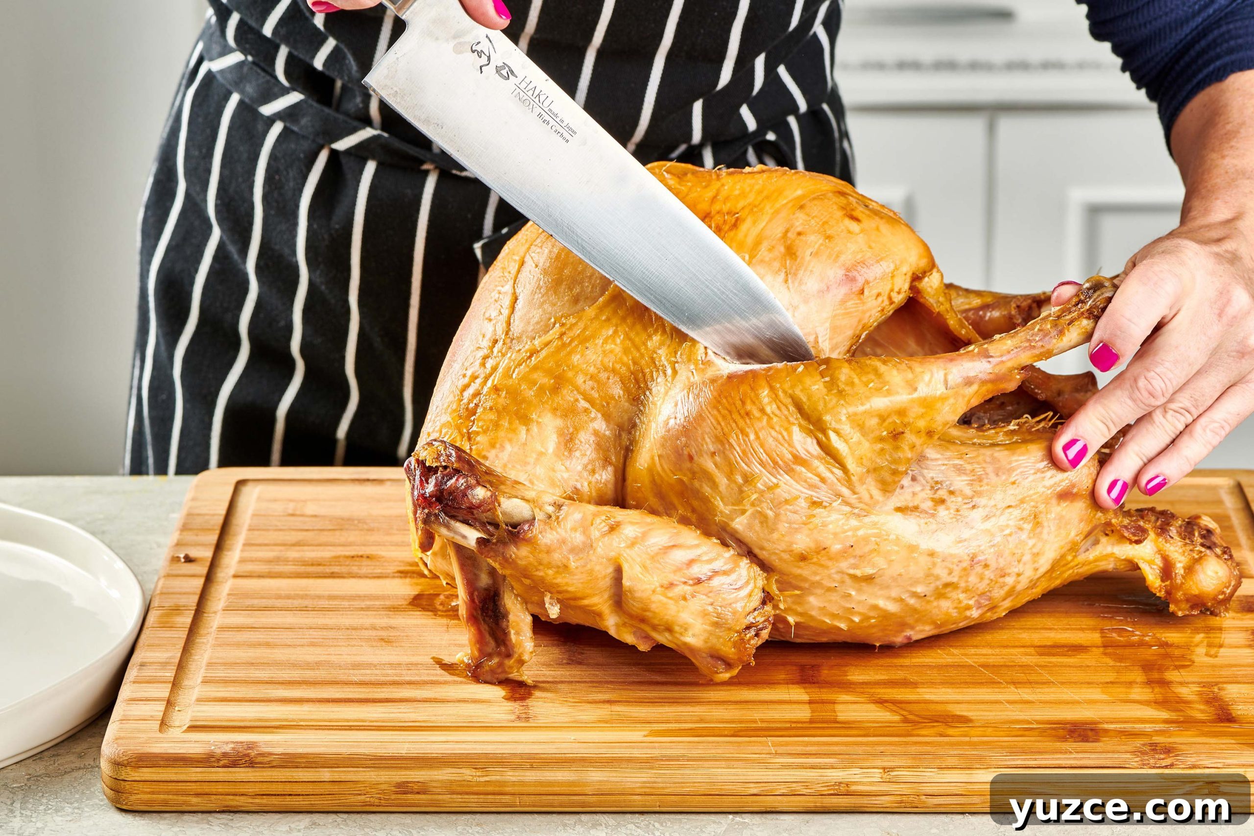 Perfect Turkey Carving Guide: Step-by-Step Tips for Juicy Slices 5 Woman removing turkey legs rom a roast turkey.