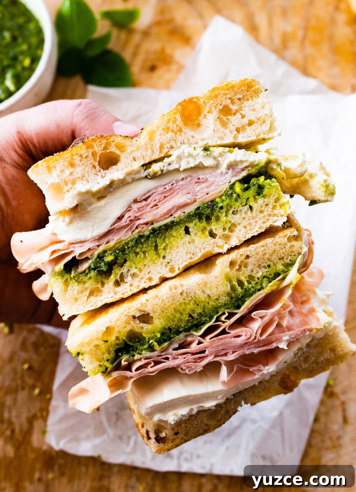 Classic Italian Mortadella Sandwich Recipe — Quick Lunch Idea 15 Assembled Mortadella Sandwich Recipe with Pistachio Pesto and Burrata with pesto on the side. Ready to eat. Hands holding the sandwiches.