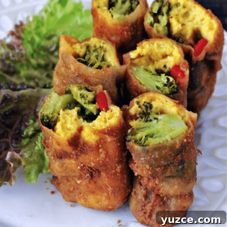 six mini vegan bacon wrapped breakfast burritos standing upright on a white plate next to leafy salad greens.