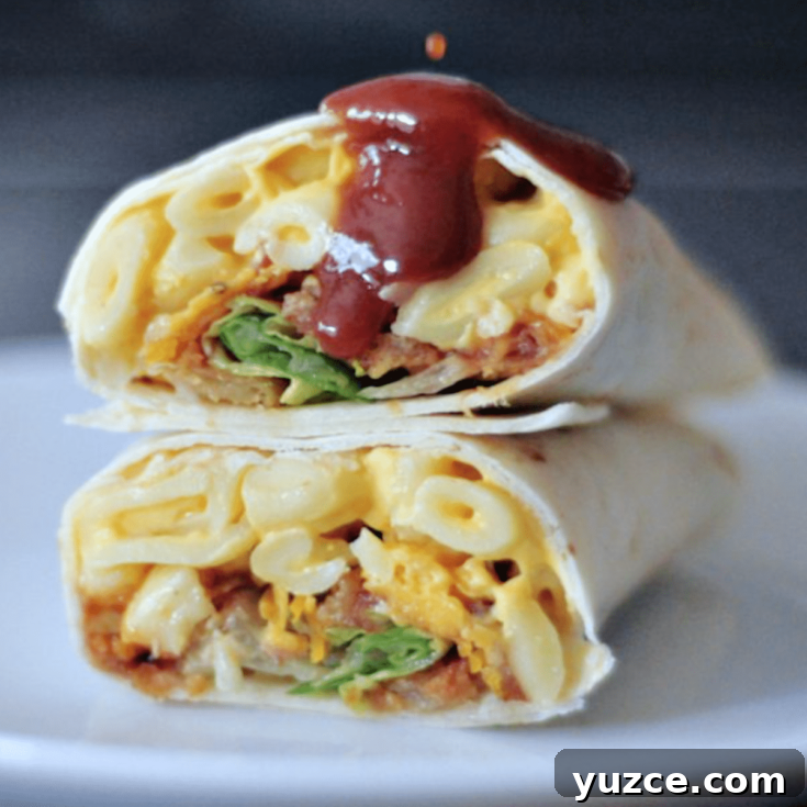 A BBQ mac and cheese burrito sliced in half on a white plate, with BBQ sauce dripping on top.