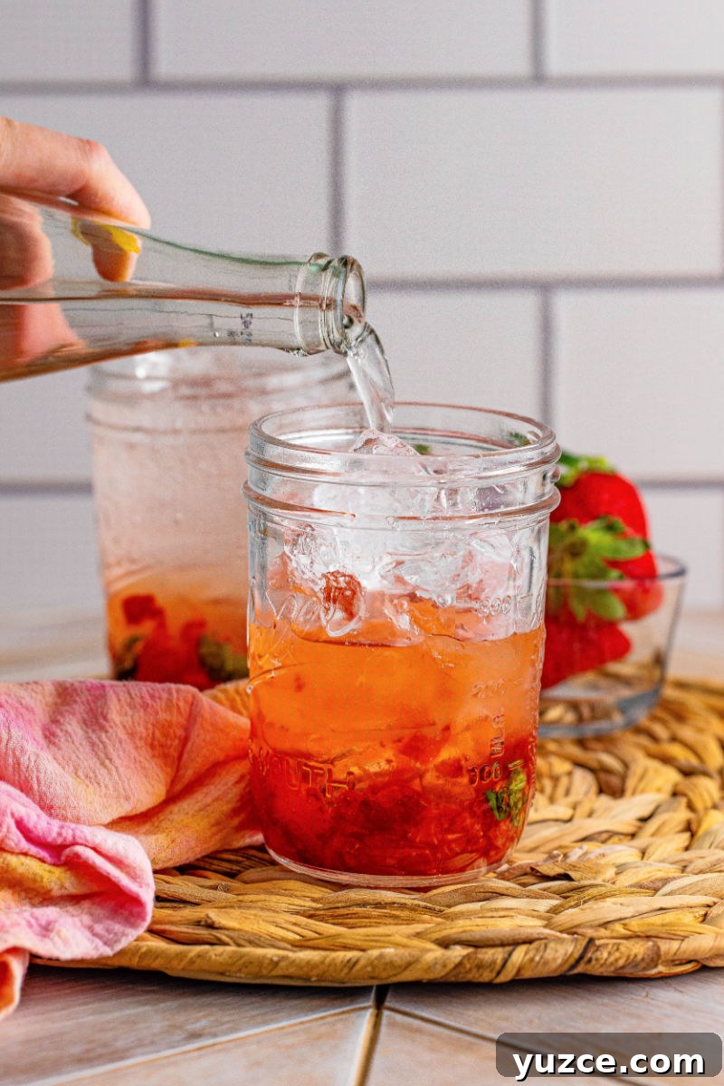 Strawberry Vodka Smash: Refreshing Summer Cocktail Recipe 7 soda water being poured into a glass with strawberry vodka smash base