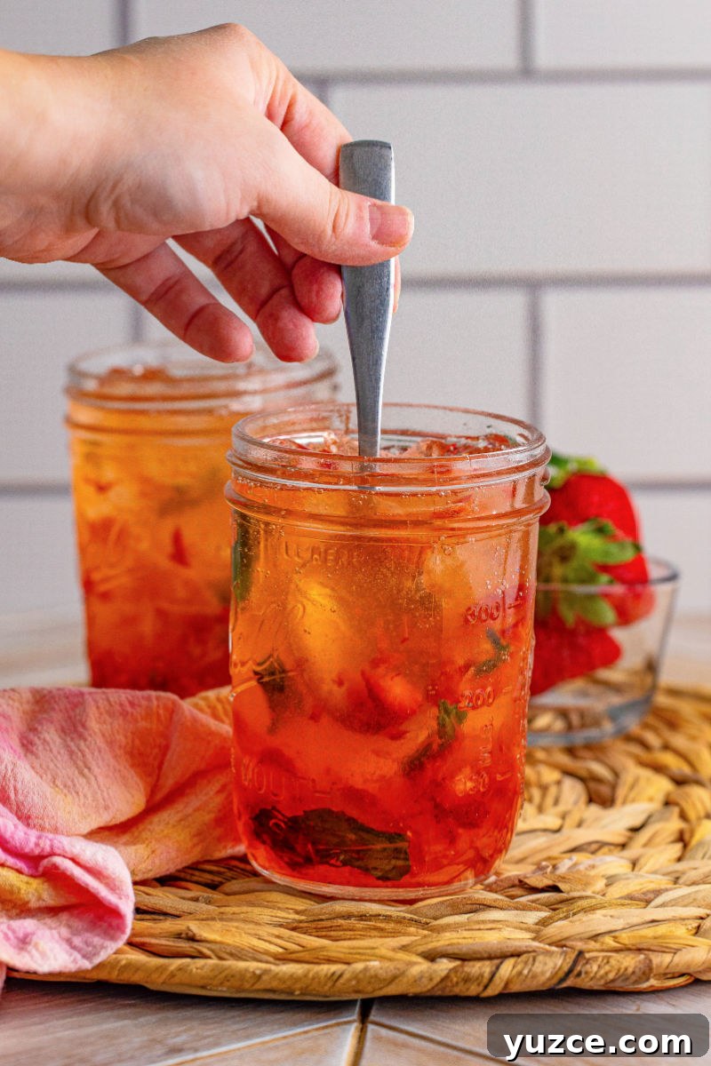 Strawberry Vodka Smash: Refreshing Summer Cocktail Recipe 8 stirring a strawberry vodka smash cocktail in a mason jar