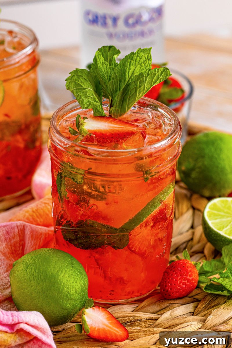 Strawberry Vodka Smash: Refreshing Summer Cocktail Recipe 9 strawberry vodka smash cocktail on a rattan tray next to limes, strawberries, and mint