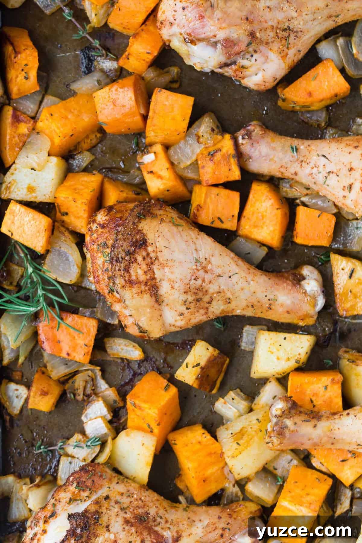 Herb-Roasted Chicken Drumsticks with Crispy Potatoes 2 Chicken drumsticks on a sheet pan with potatoes.