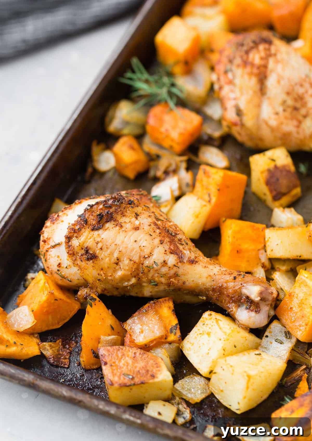Herb-Roasted Chicken Drumsticks with Crispy Potatoes 3 Roasted chicken drumsticks on a pan with potatoes and onions.
