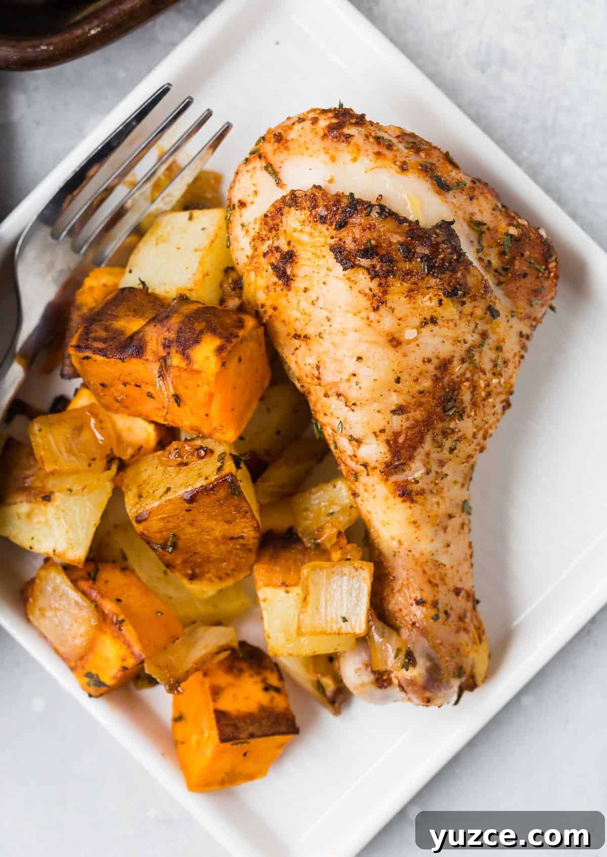Herb-Roasted Chicken Drumsticks with Crispy Potatoes 4 Chicken drumstick and roasted potatoes on a plate.