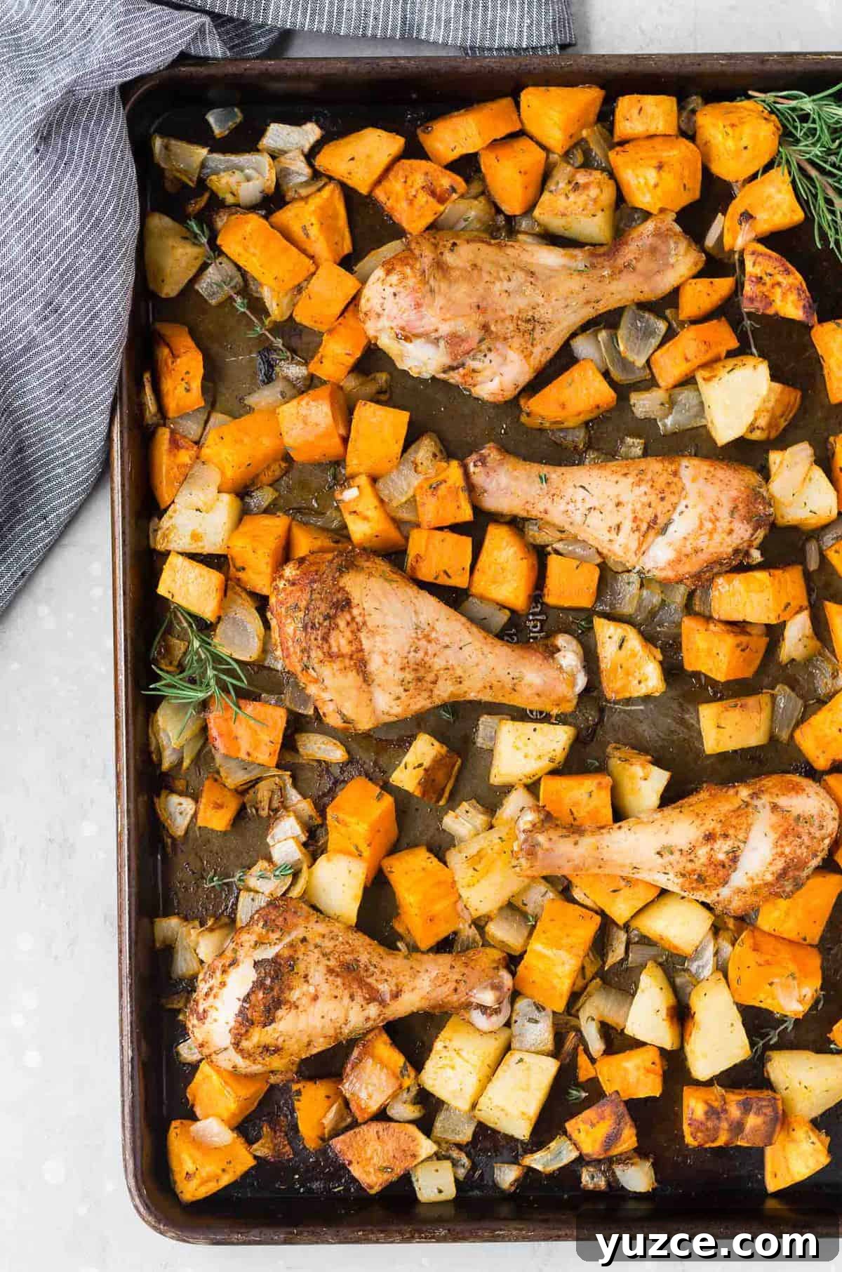 Herb-Roasted Chicken Drumsticks with Crispy Potatoes 7 Overhead view of a sheet pan full of roasted potatoes, sweet potatoes, onions, and spice-rubbed drumsticks.