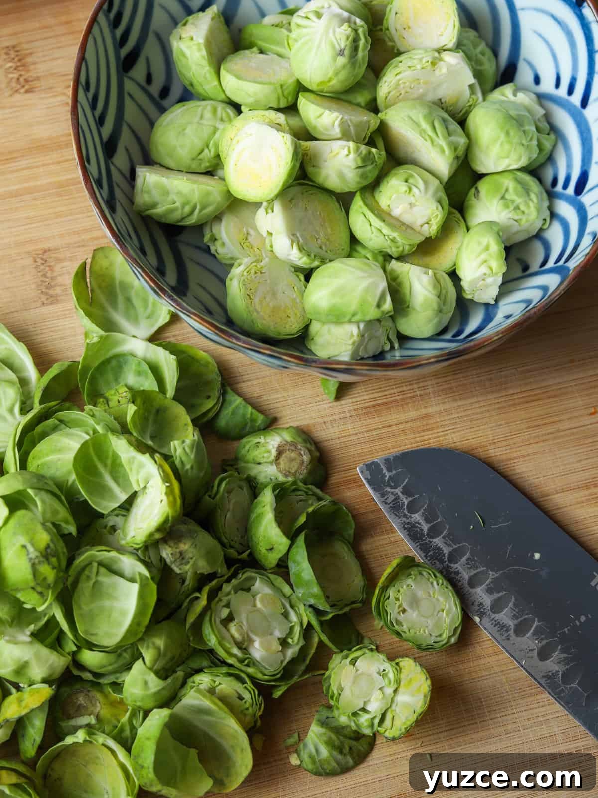 Smoky Roasted Brussels Sprouts with Chestnuts (Vegan) 4 Photo of a bowl of prepped sprouts on a chopping board with the peelings and a knife in the foreground.