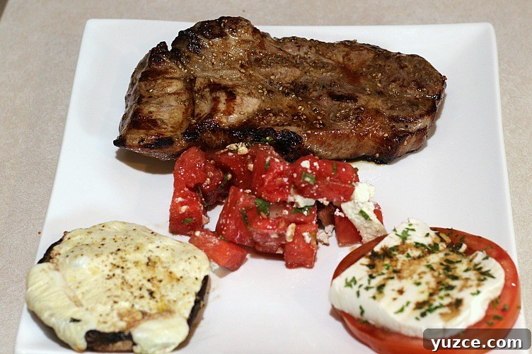 Cheese-Stuffed Portobello Mushrooms Recipe for Weeknight Dinner 5 Grilled Pork steak, grilled portabella mushrooms, tomato caprese, and watermelon salad on a white plate