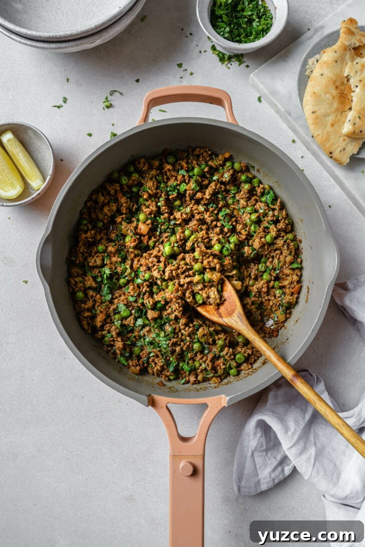 Keema Matar: Spiced Ground Beef and Pea Curry Recipe 2 Keema Matar in a skillet with a wooden spoon.