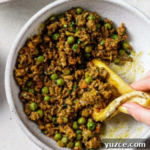 Keema Matar: Spiced Ground Beef and Pea Curry Recipe 12 Scooping up Keema Matar with a piece of naan.