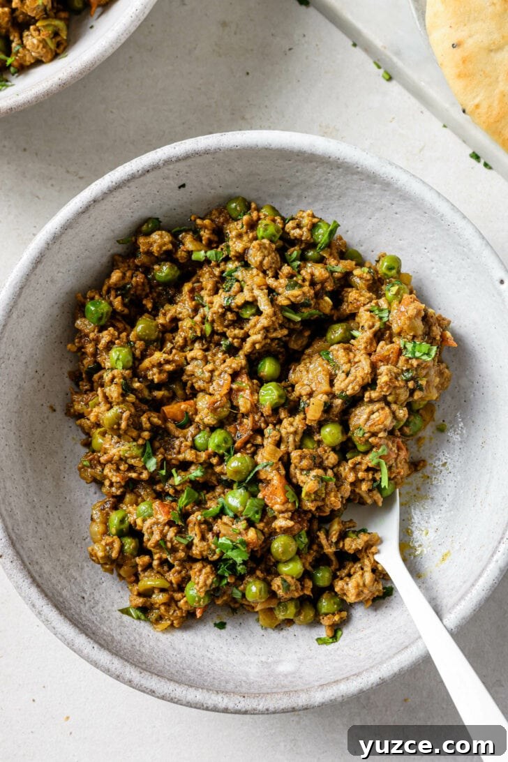 Keema Matar: Spiced Ground Beef and Pea Curry Recipe 4 Close up of Keema Matar in a bowl with a spoon.