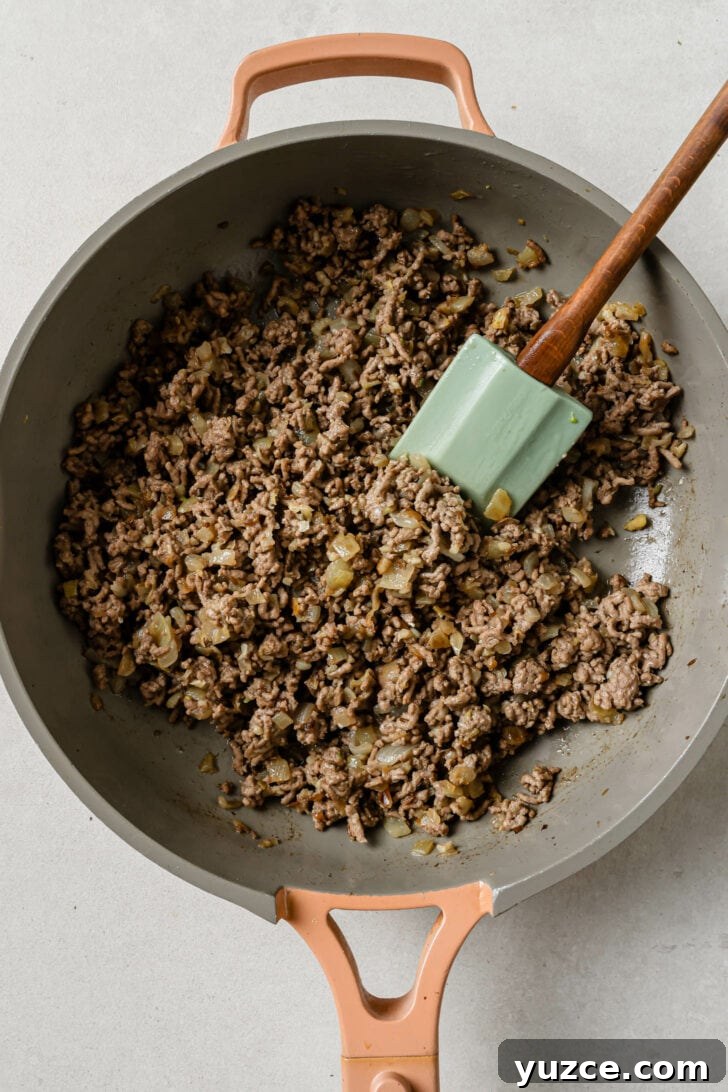 Keema Matar: Spiced Ground Beef and Pea Curry Recipe 8 Sauteed ground beef in a skillet with a rubber spatula for Keema Matar.