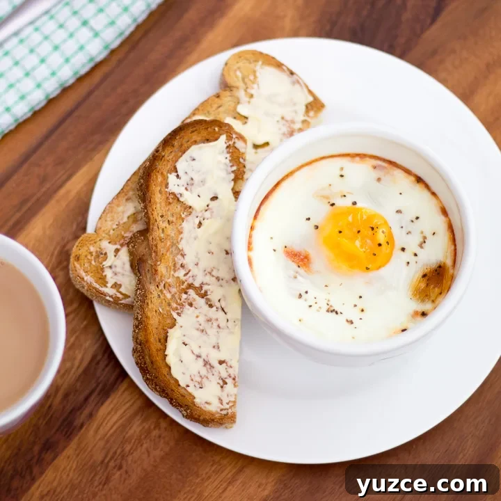 Tomato baked eggs on a plate with buttered toast and a cup of tea