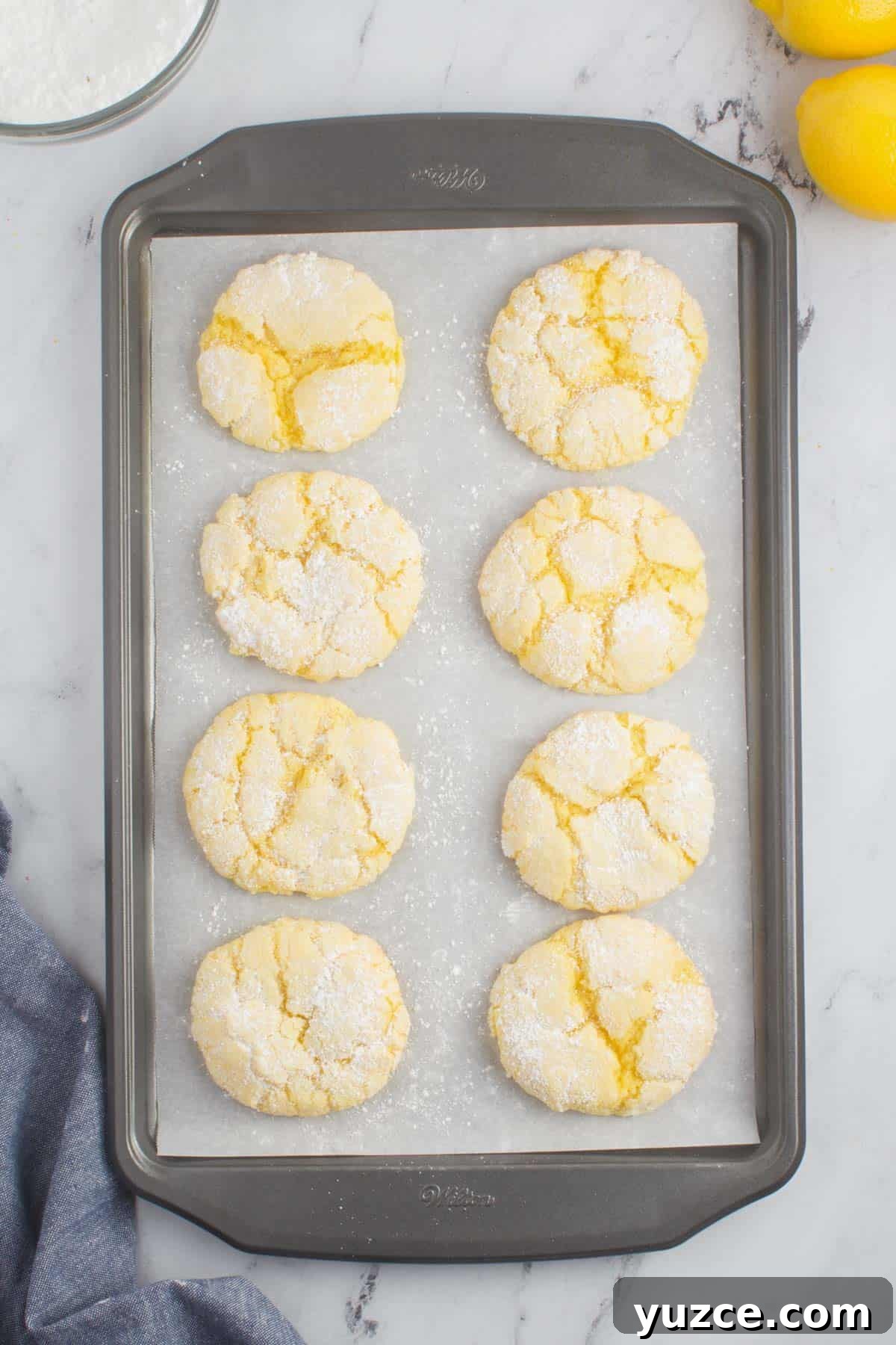 Chewy Lemon Cake Mix Cookies: Quick Citrus Cookie Recipe 3 eight lemon cake mix cookies on a baking sheet lined with parchment paper sitting on a granite counter