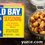 Overhead look at a glass jar filled to the top with Old Bay & bacon peanuts next to a can of old bay seasoning.
