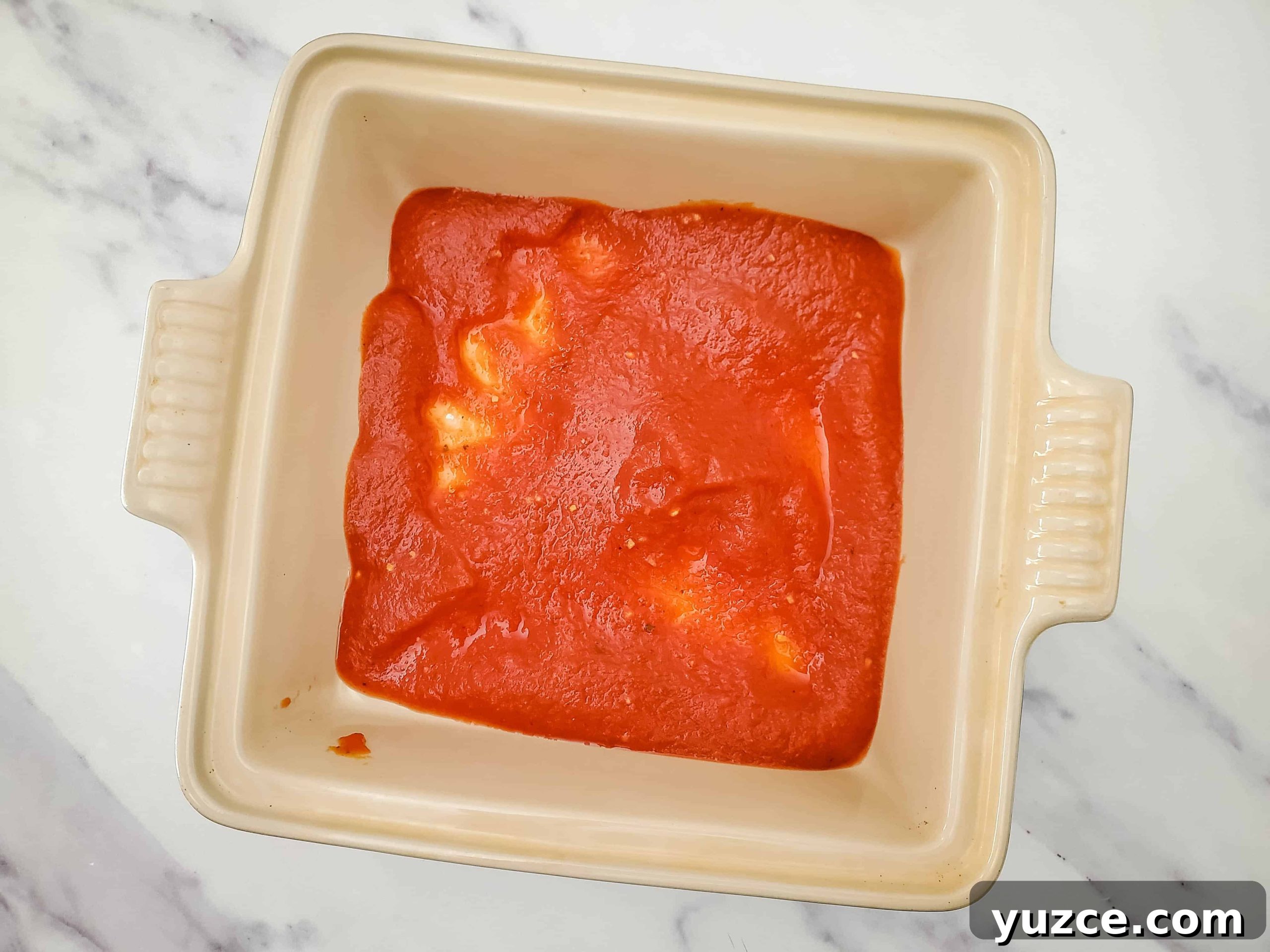 Quick Ravioli Lasagna Recipe for Busy Weeknight Dinners 4 Glass baking dish with layer of pasta sauce evenly distributed