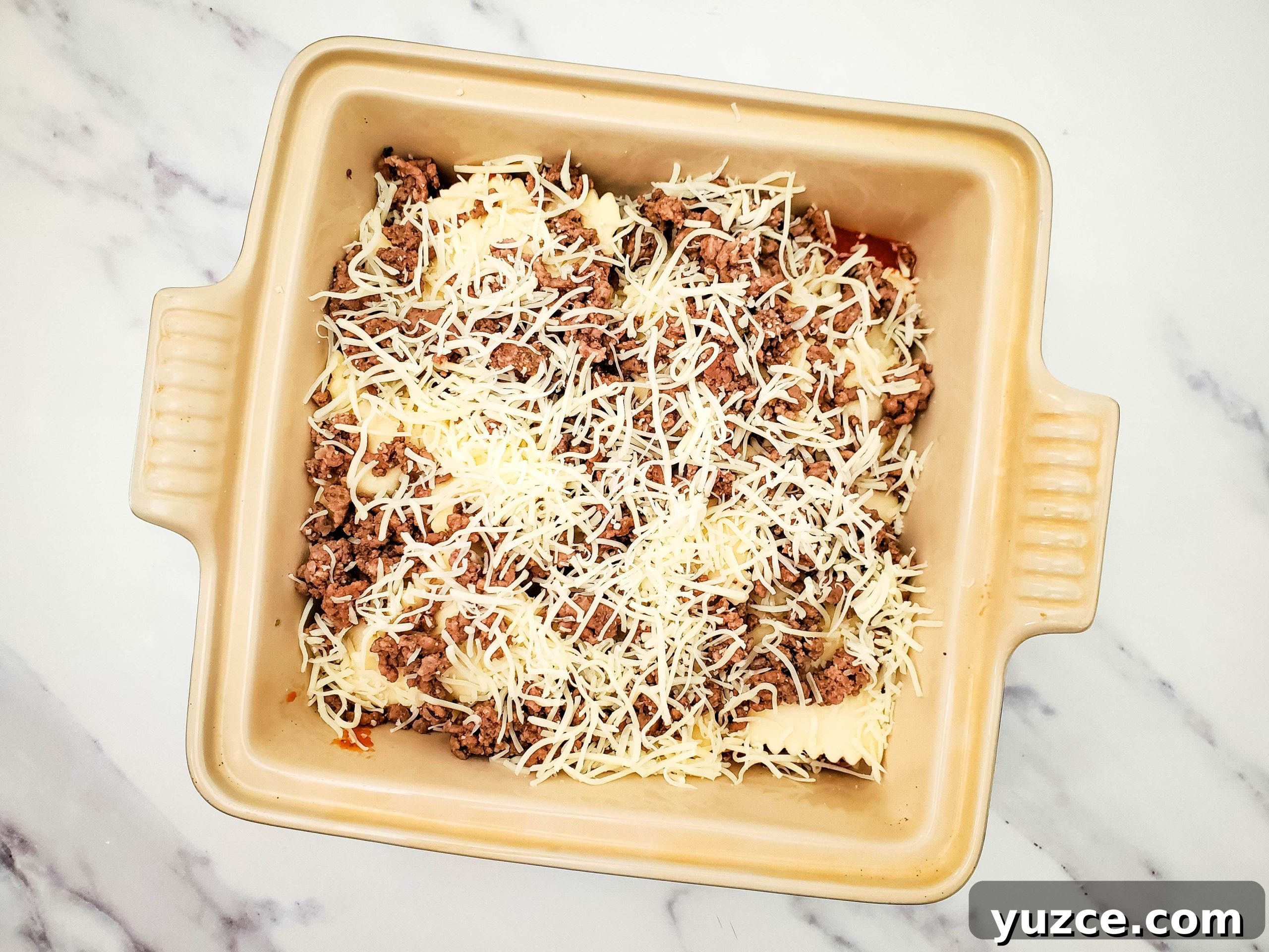 Quick Ravioli Lasagna Recipe for Busy Weeknight Dinners 6 Casserole baking dish with layered pasta sauce, frozen ravioli, ground beef, and mozzarella cheese