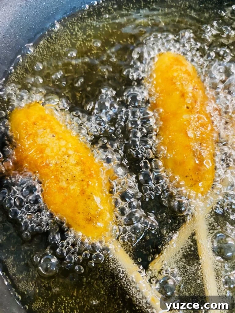Sausage Pancake Corn Dogs Recipe: Crispy Breakfast on a Stick 8 breakfast dogs frying in oil