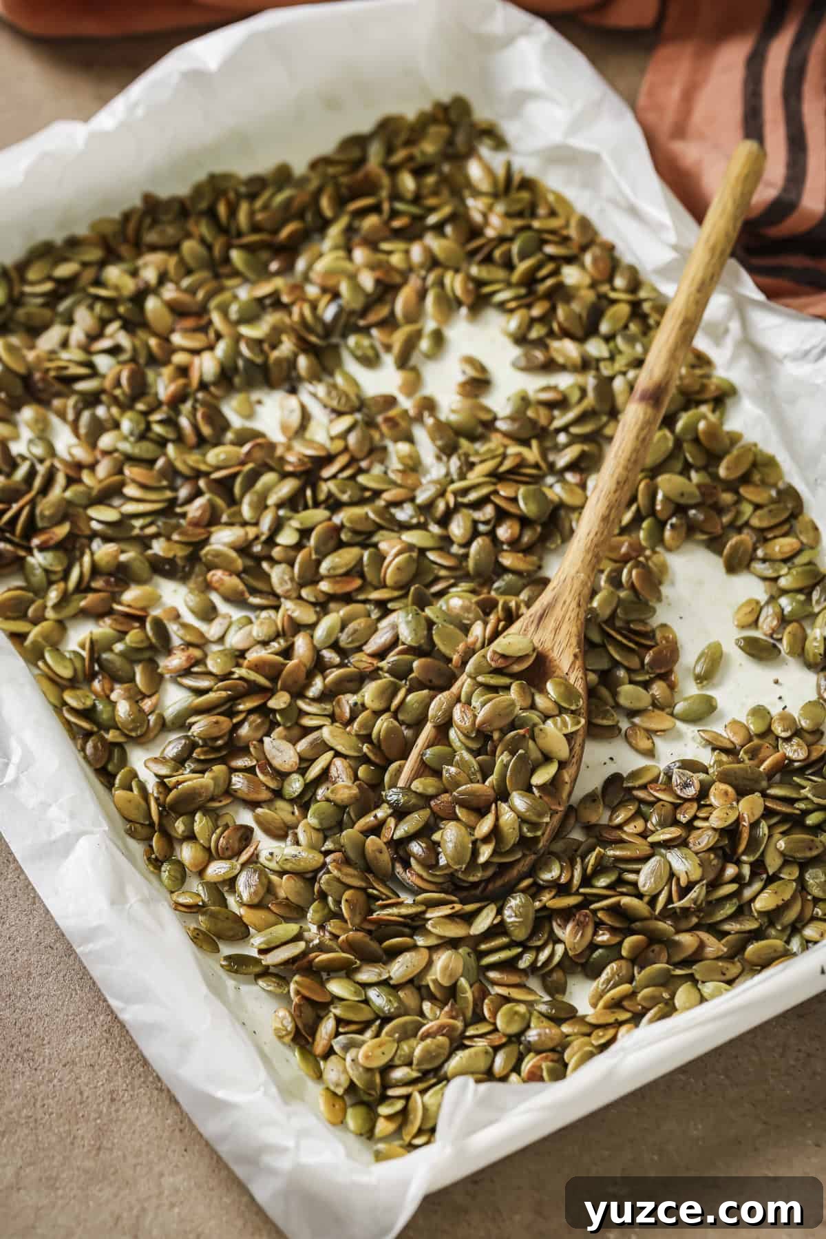 Crispy Oven-Roasted Pepitas with Sea Salt 10 roasted pepitas on a parchment paper lined sheet pan.