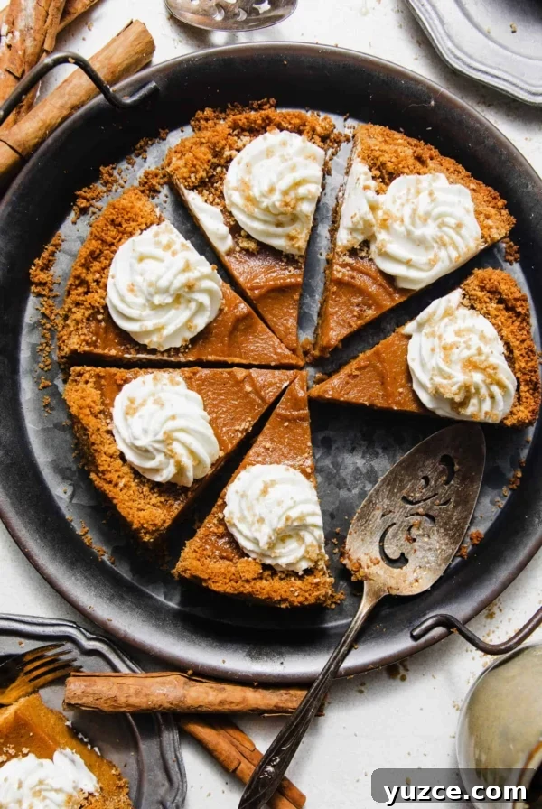 sliced sweet potato pie with graham cracker crust on a silver platter topped with whipped cream